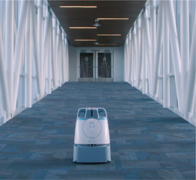 Robot moving through a modern hallway.